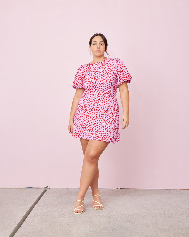 ESME TIE MINIDRESS PINK SCATTER HEARTS | Bias cut minidress with puff sleeves, waist tie and a keyhole button closure at the back neck. Designed in our RUBY 'scatter hearts' print, the bias silhouette of this dress...