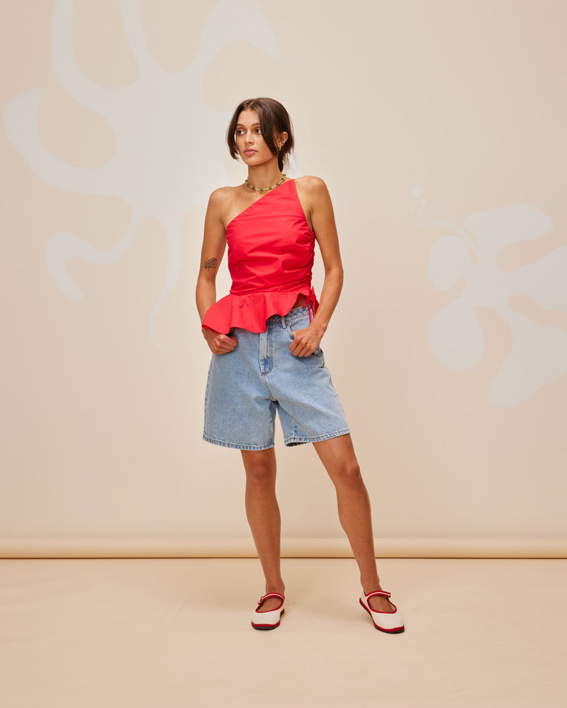 BETTINA COTTON TOP CHERRY | One shoulder cotton top with tie side gathering that can be cinched to adjust the length. The asymmetrical shape creates structure, while the peplum ruffle at the bottom hem adds...