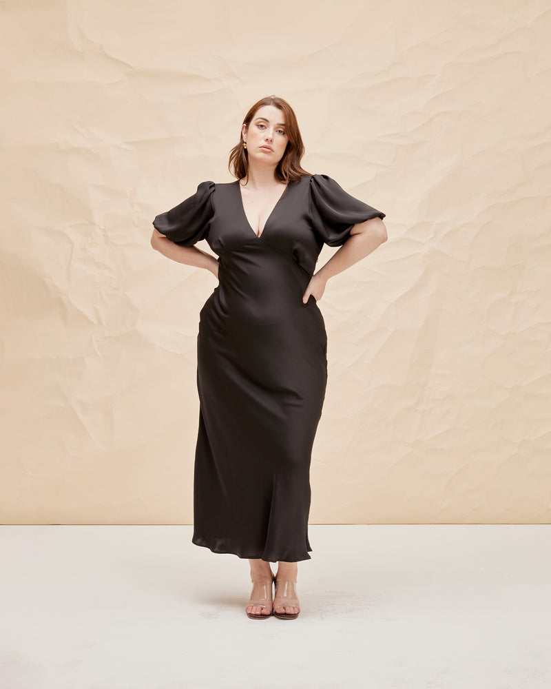 UMA SATIN DRESS BLACK | Bias cut satin maxi dress with tie closure and a V-neck front and back. Our much loved Uma Dress is back in a black satin, with elasticated puff sleeves and...