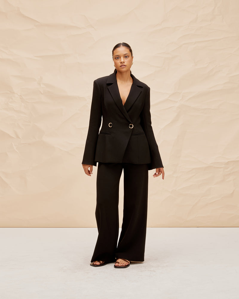 FRANKA PANT BLACK | Highwaisted wide leg pant with a crossover waistband. The waistband is thick and fits closely to the form, while our new suiting fabric creates structure in the leg.