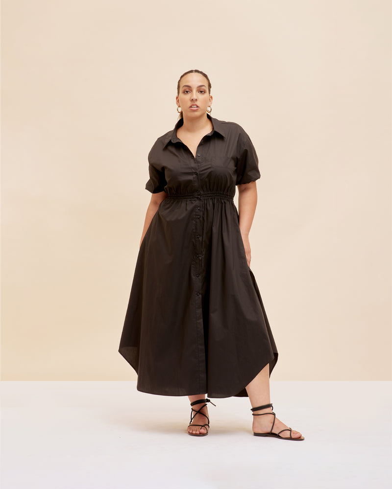 COMET SHIRT DRESS BLACK | Maxi shirt dress crafted in a black cotton with an elasticated waist and short sleeves. The fully functional buttons allow you to show as little or as much skin as...