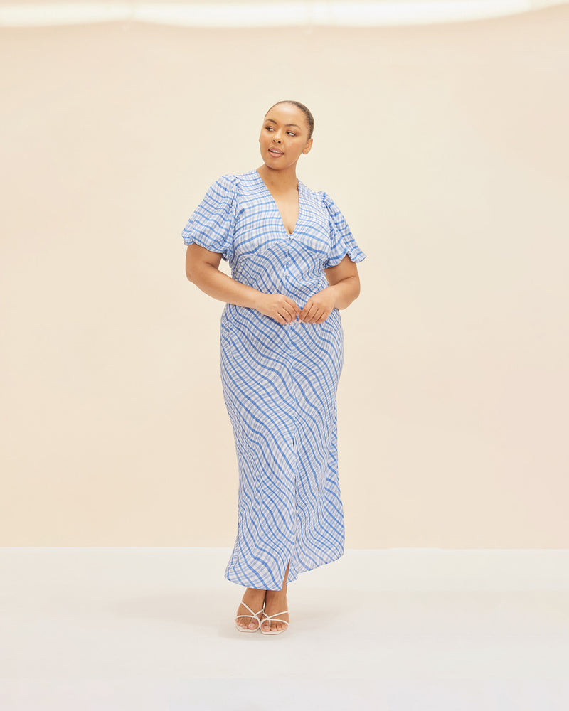 NEPTUNE SILK MIDI DRESS BLUE CHECK | Bias cut puff sleeve maxi dress crafted in our RUBY blue waves print with self covered buttons down the front and a centre front split. The silk creates a beautiful...