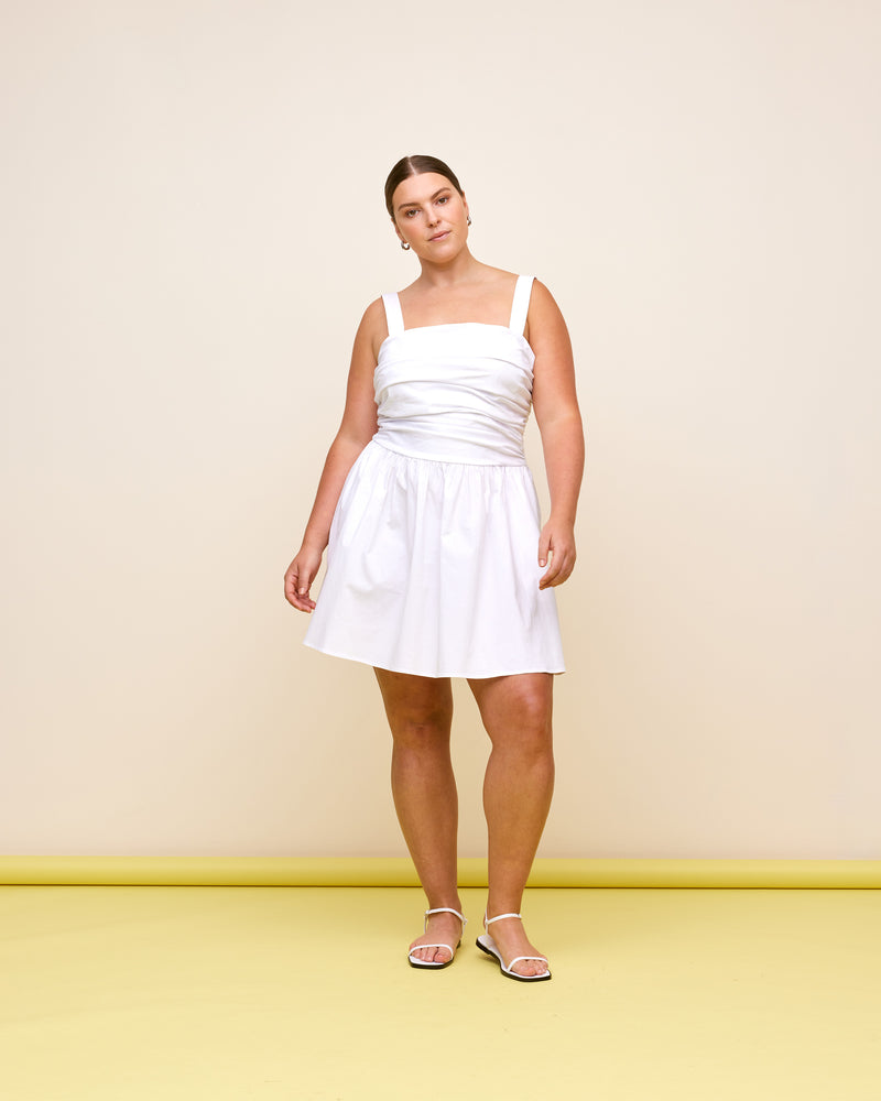 ARIEL MINI DRESS  WHITE | Sleeveless white cotton dress with a ruched body. This dress has a dropped waist that falls to a full gathered mini skirt.