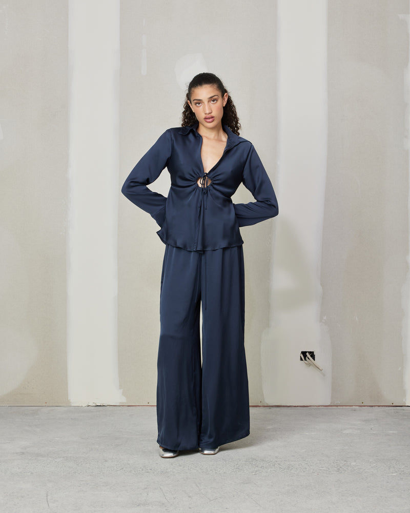 CALVIN TIE SHIRT INK | Satin shirt with a feature drawstring keyhole at the bust, creating gathers fanning out across the shirt. The shirt has full length sleeves with a slight flared silhouette, created by...