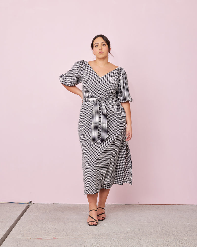 GEN GINGHAM MIDI DRESS BLACK LADDER GINGHAM | Bias cut v-neck gingham midi dress with puff sleeves. With a detachable waist tie and the option to wear on or off the shoulder, this dress is a versatile and...
