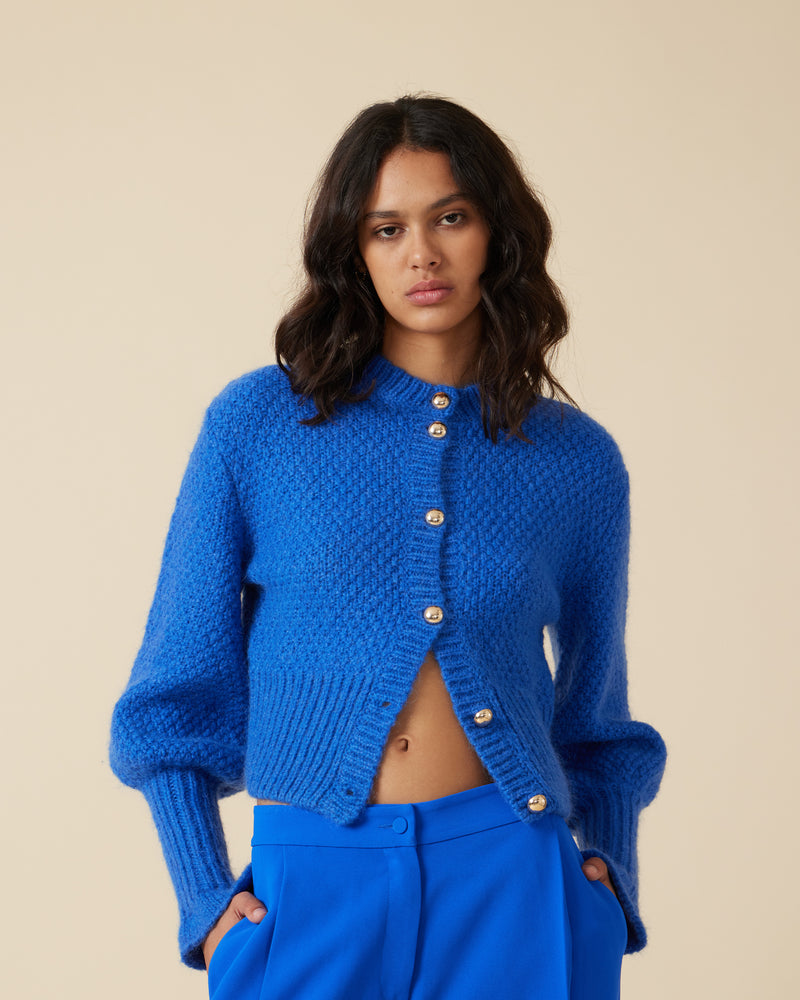 MATILDA CARDIGAN SAPPHIRE | 
Button-down cardigan with gold metallic dome buttons and a slightly puff-shouldered silhouette. Features an exaggerated flute cuff crafted in a chunky alpaca and wool blend.