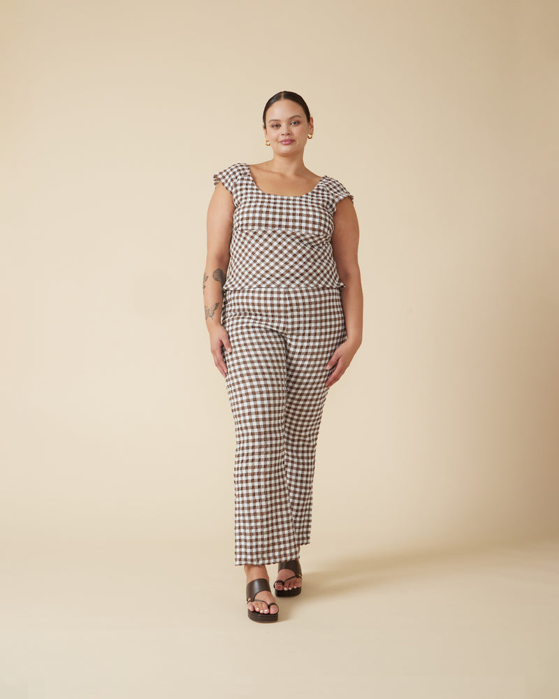 PRISM TOP BROWN GINGHAM | Cap sleeve top cut in a stretch gingham fabric that has a gathered, seersucker texture. The round neckline falls to be scooped at the back. This top is an easy...