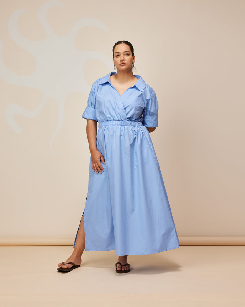 SOOKIE SHIRTDRESS CORNFLOWER | Maxi shirt dress crafted in cornflower cotton with an elasticated waist and short sleeves. This dress is designed with a faux wrap detail with a feature front pocket.