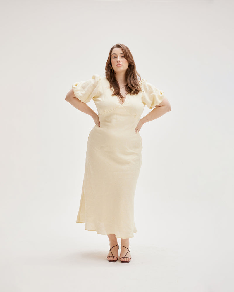 UMA LINEN DRESS LEMONADE | Bias cut linen maxi dress with tie closure and a V-neck front and back. Back in a new lemonade coloured linen, with elasticated puff sleeves and ruched detailing under the...