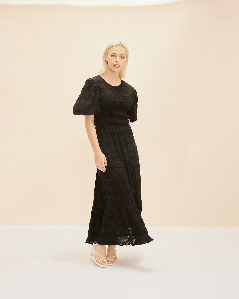 MIRELLA PRAIRIE DRESS BLACK | A-line maxi dress that is fitted through the top and continues into a floaty skirt, with a round neckline and short elasticated puff sleeves. The voluminous sleeves make this silhouette...