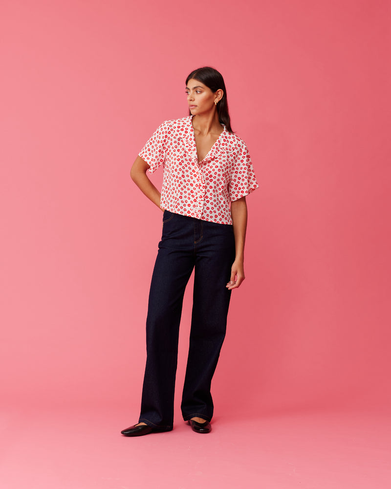KAARINA SILK SHIRT RED DAISY | Short sleeve silk shirt with ruffles down the placket and a rounded collar. Designed in our RUBY red daisy print, this shirt can be styled as a layering piece or...