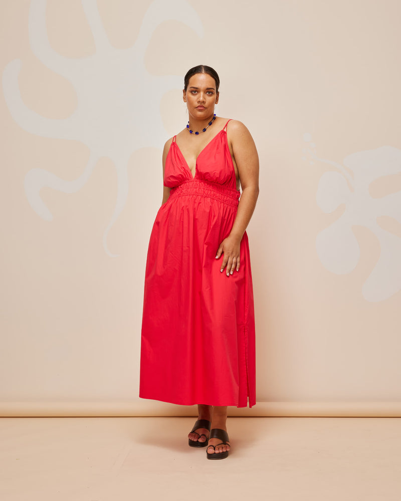 HERO MAXI DRESS CHERRY | Double strap maxi dress with a plunge neckline, shirred waist detail, and side split in a cherry red cotton. The shirring at the waist accentuates the full skirt.