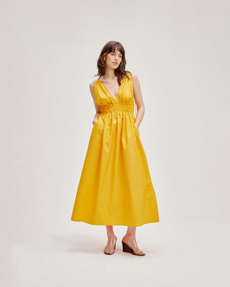 HERO MAXI DRESS MARIGOLD | Double strap cotton maxi dress with a plunge neckline, shirred waist detail and side split in a striking marigold colour. The shirring at the waist accentuates the full skirt.