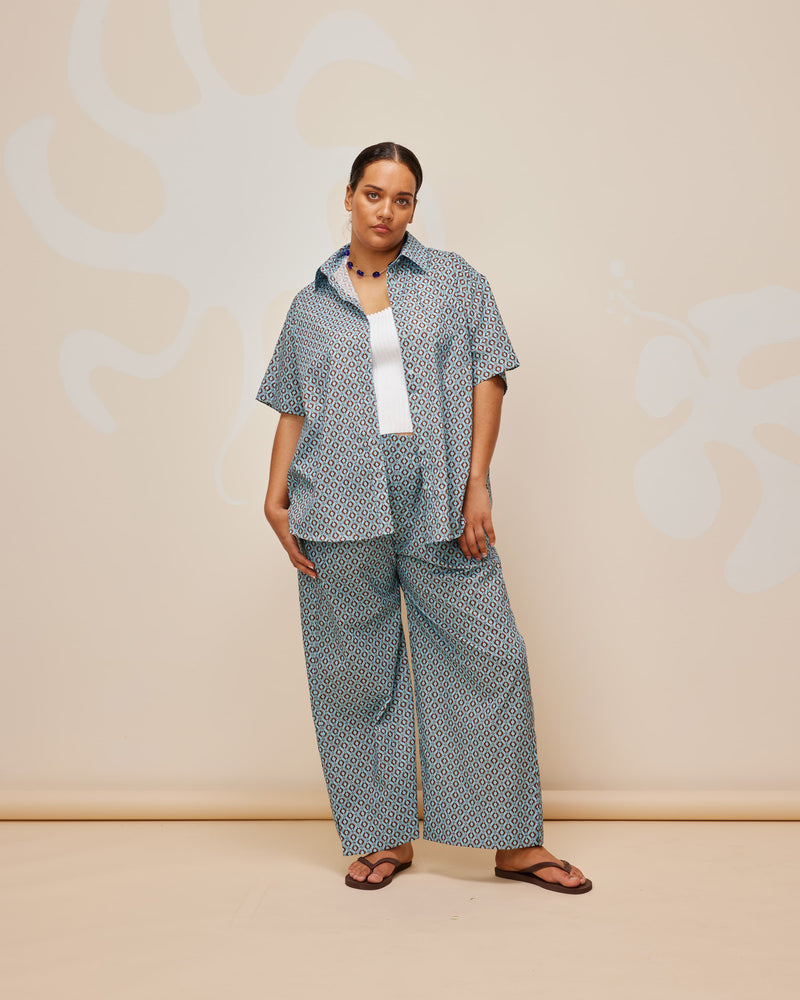 JEAN PANT GEOMETRIC PRINT | Straight leg cotton pant with an elastic waistband, designed in blue and brown geo print cotton. These pants sit relaxed and wide and have side and back pockets. Crisp and...