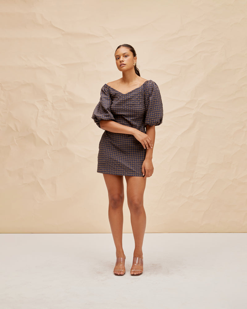 BON GINGHAM MINIDRESS NAVY BROWN GINGHAM | Cotton mini dress cut in a navy and brown gingham with elasticated puff sleeves and a wide v neckline. The sleeves can be worn on or off the shoulder.