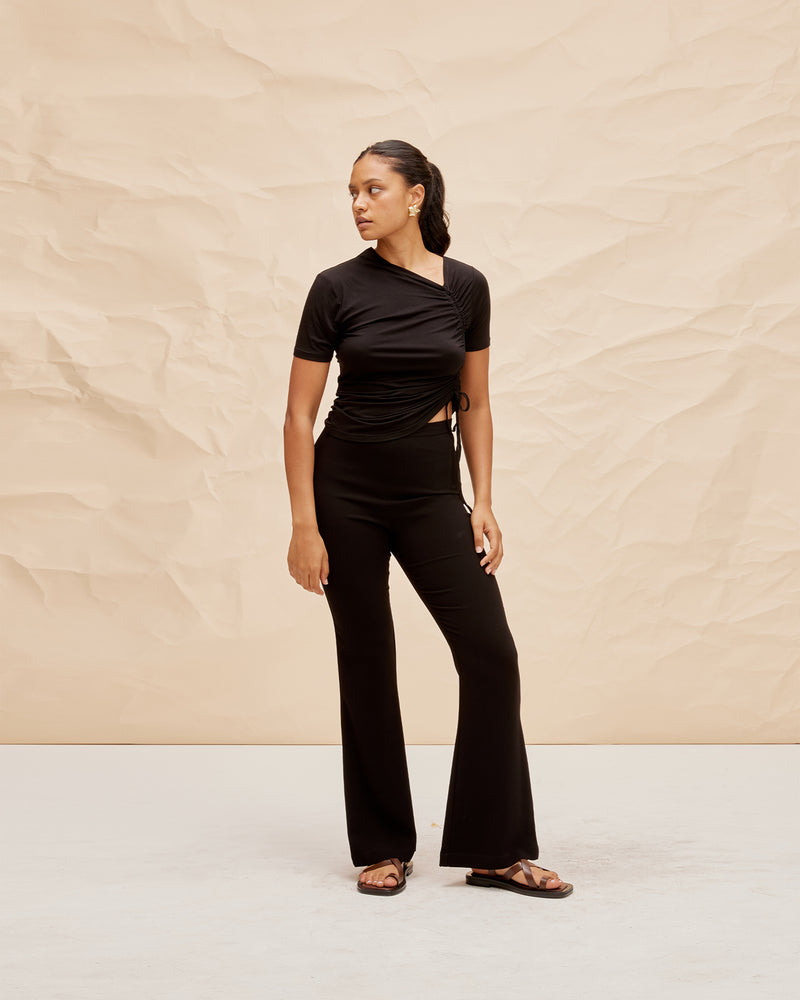 TOBY T-SHIRT BLACK | Short sleeve knit top with an asymmetrical neckline and a drawstring detail at the side of the piece that creates ruching in soft folds. Cut for a close fit, the...