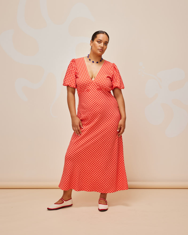 UMA DRESS STRAWBERRY PEACH GINGHAM | Bias cut linen maxi dress with tie closure and a V-neck front and back. Cut in vibrant strawberry and peach gingham, with elasticated puff sleeves and ruched detailing under the bust,...
