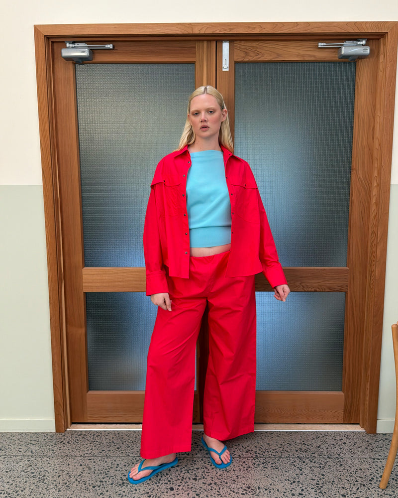SONNY SHIRT CHERRY | Relaxed crisp shirt with classic shirt detailing and a snap dome closure, designed in a vibrant red cherry cotton poplin. A statement piece on it's own, or make it a matching set with the Sonny Pant.