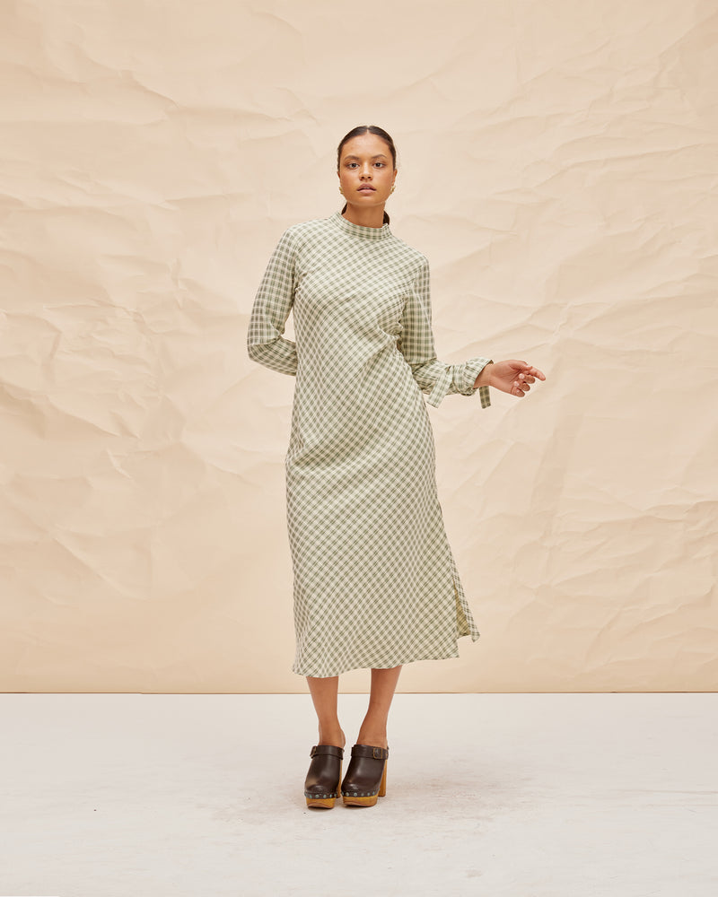 CONNIE DRESS GREEN CHECK | Longsleeve midi dress with a high neckline and ties at the back neck and cuffs cut in a green check fabric. Features a side split and bias cut for ease of movement.