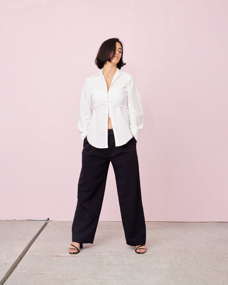 ARIEL SHIRT WHITE | A new take on the classic white shirt, featuring rouched detailing across the bust and a hook and eye down front. The ruched band gives the this shirt a layered look.