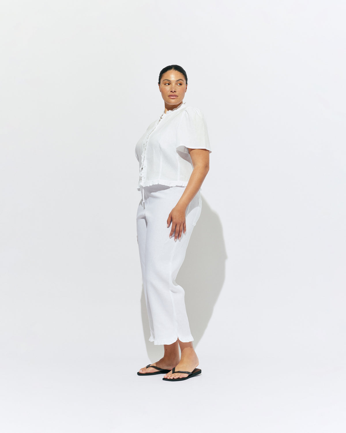 ARLO LINEN TOP WHITE | White linen button up blouse with ruffle detailing around the neckline, hem and down the front. A great addition to your workwear wardrobe, pair with denim for a sweet and simple look. 