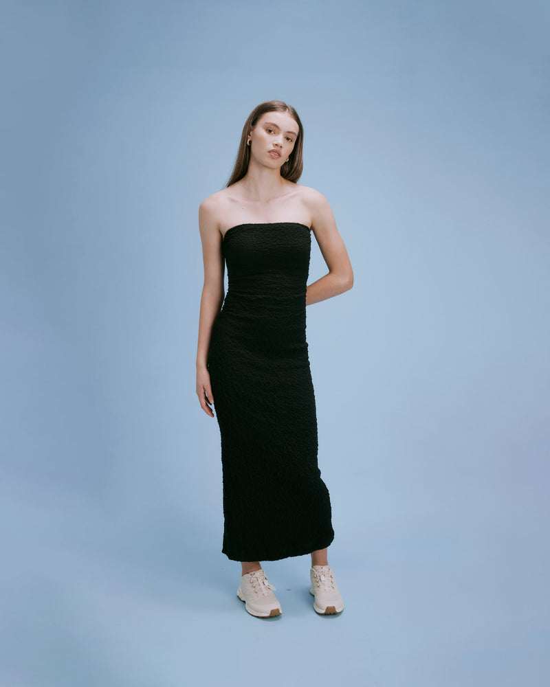 BUBBLE DRESS BLACK | Fitted strapless midi dress with a split at the back allowing for ease of movement. Woven into a tactile story as reflected in its name, the textured element adds a...
