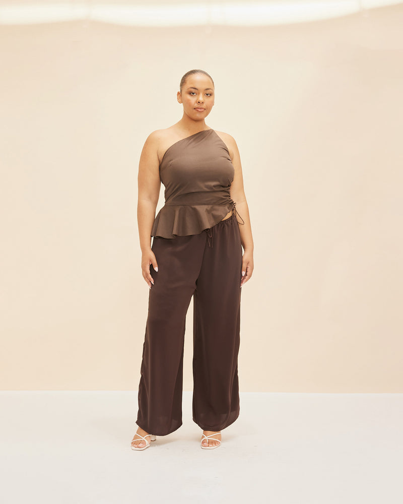 BETTINA COTTON TOP CHOCOLATE | One shoulder cotton top with tie side gathering that can be cinched to adjust the length. The asymmetrical shape creates structure, while the peplum ruffle at the bottom hem adds...