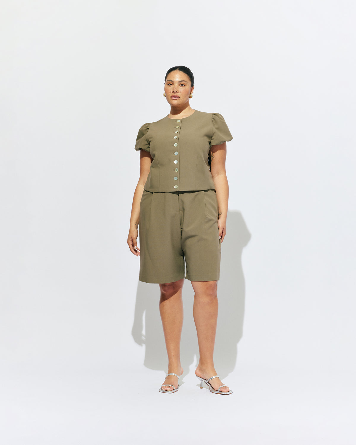 CAROLYN PUFF SLEEVE BLAZER MARTINI OLIVE | Collarless short sleeve blazer with feature pearlescent buttons and puff sleeves.  An elevated classic with a structured silhouette, this top is the perfect addition to your everyday workwear rotation. Pair with our Coco Suit Short for a matching moment, or...