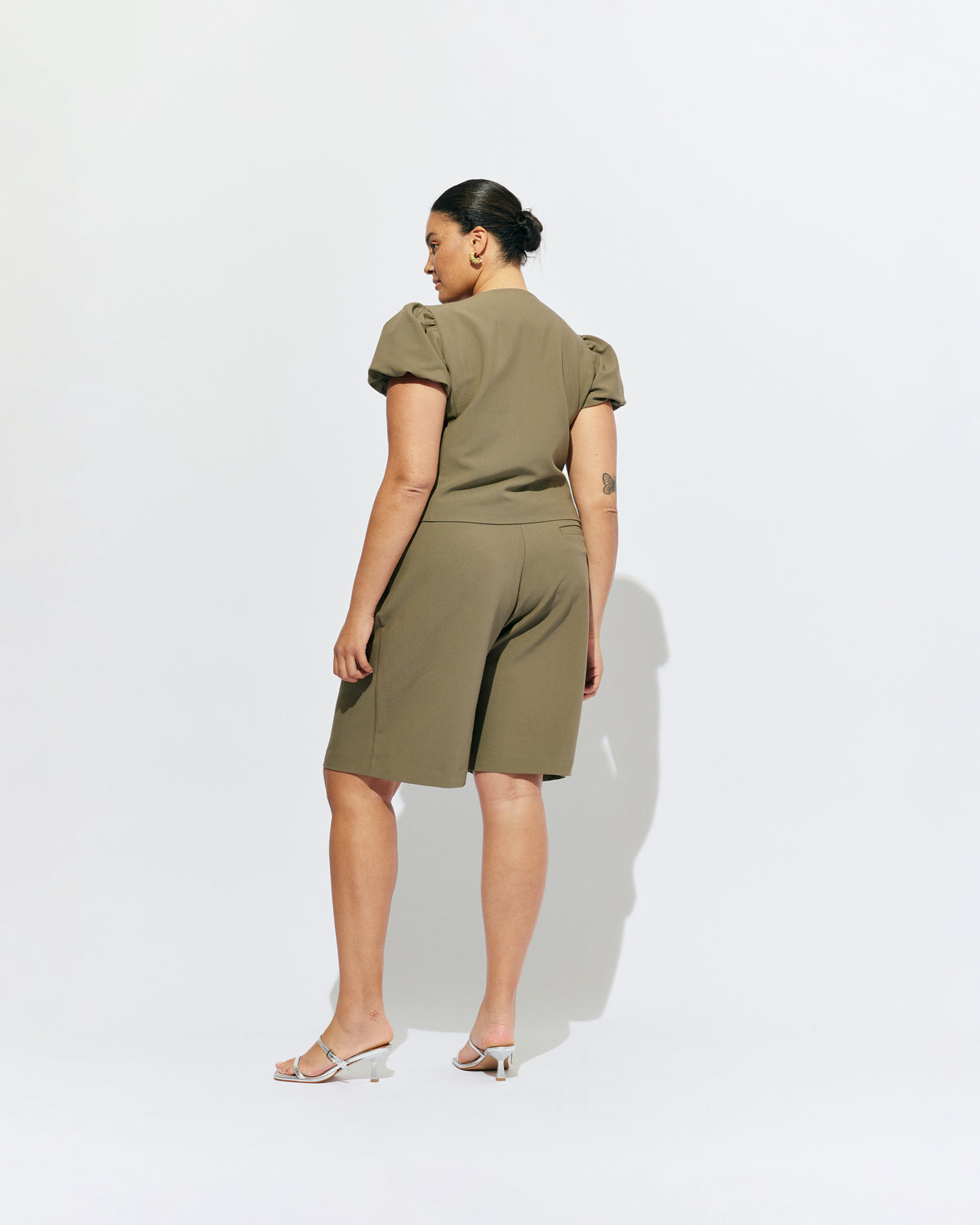 CAROLYN PUFF SLEEVE BLAZER MARTINI OLIVE | Collarless short sleeve blazer with feature pearlescent buttons and puff sleeves.  An elevated classic with a structured silhouette, this top is the perfect addition to your everyday workwear rotation. Pair with our Coco Suit Short for a matching moment, or...