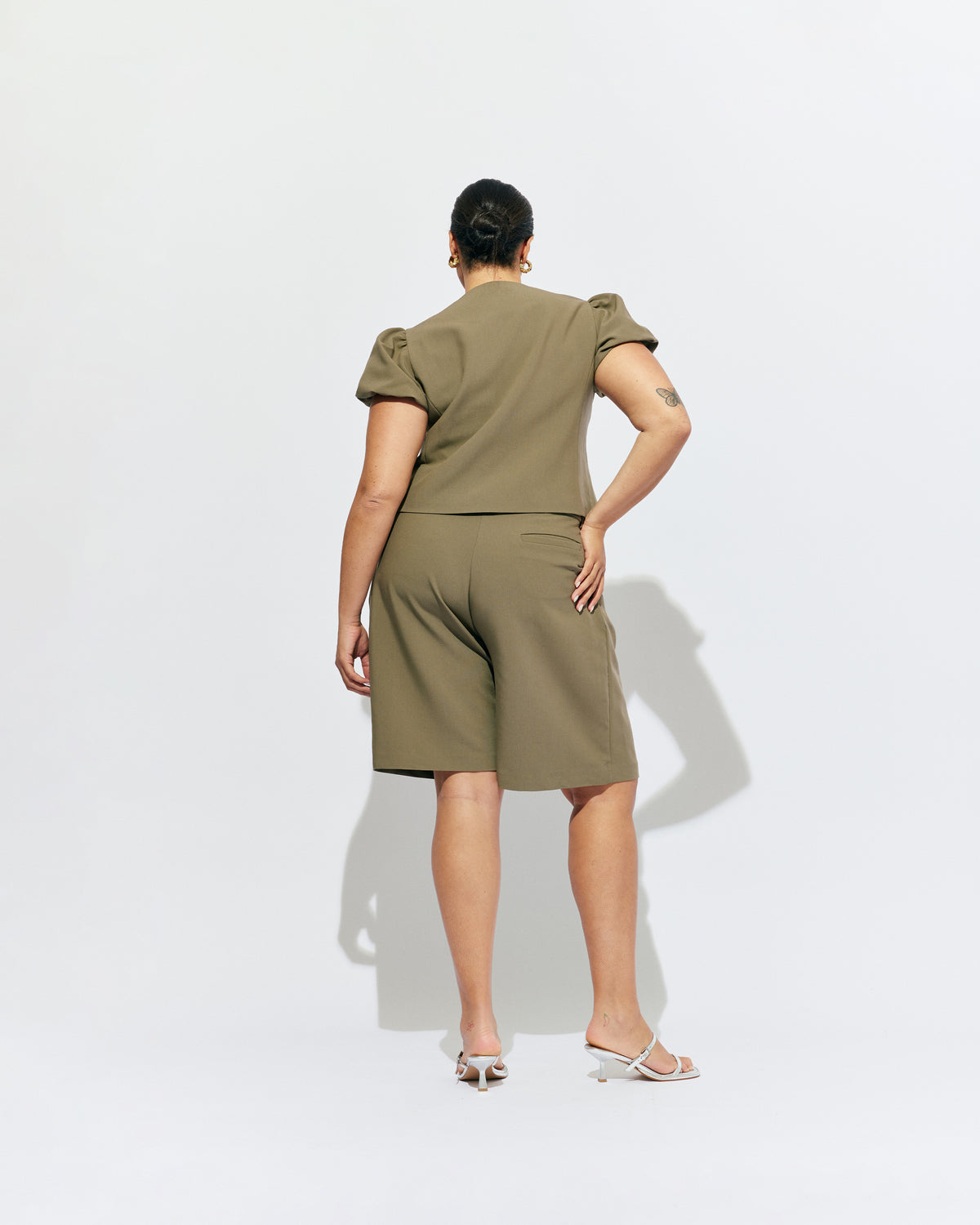CAROLYN PUFF SLEEVE BLAZER MARTINI OLIVE | Collarless short sleeve blazer with feature pearlescent buttons and puff sleeves.  An elevated classic with a structured silhouette, this top is the perfect addition to your everyday workwear rotation. Pair with our Coco Suit Short for a matching moment, or...