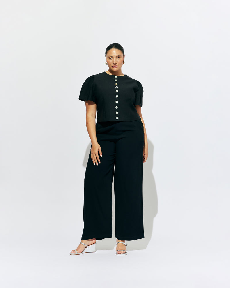 CAROLYN SHORT SLEEVE BLAZER BLACK | Collarless short sleeve black blazer with feature pearlescent buttons.  An elevated classic with a structured silhouette, this top is the perfect addition to your everyday workwear rotation. Pair with your favourite trousers, or denim for a more casual look.