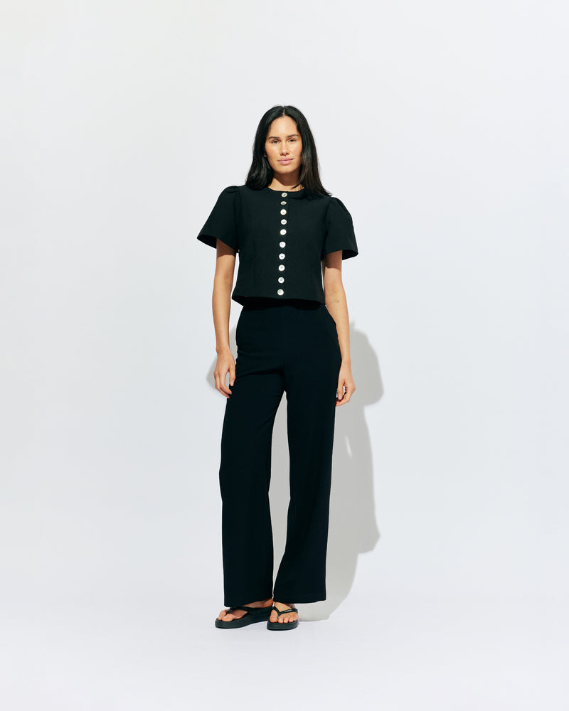 CAROLYN SHORT SLEEVE BLAZER BLACK | Collarless short sleeve black blazer with feature pearlescent buttons.  An elevated classic with a structured silhouette, this top is the perfect addition to your everyday workwear rotation. Pair with your favourite trousers, or denim for a more casual look.
