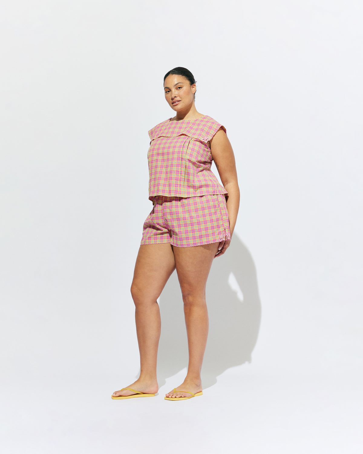 CRUSH BLOUSE PINK YELLOW TARTAN | Sleeveless blouse featuring an oversized sailor-style collar with a scalloped hem and broderie detailing on the sides, designed in our organic cotton pink yellow tartan. Features a button up design at the back, which can be worn open to keep...