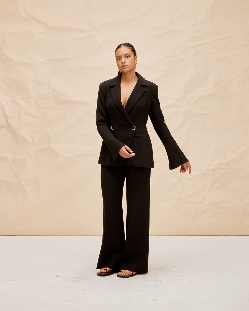 FRANKA BLAZER BLACK | Double breasted fitted blazer with an asymmetrical closure at the front. The fitted silhouette creates definition at the waist and this shape is also reflected in the fluted sleeve detail.