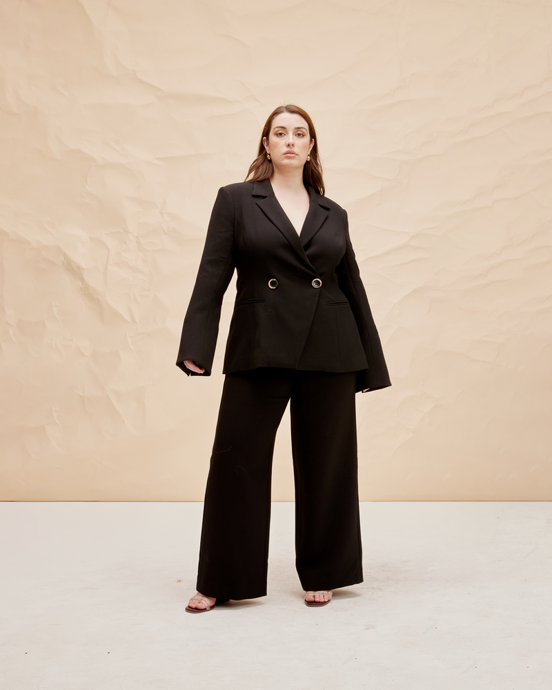 FRANKA BLAZER BLACK | Double breasted fitted blazer with an asymmetrical closure at the front. The fitted silhouette creates definition at the waist and this shape is also reflected in the fluted sleeve detail.