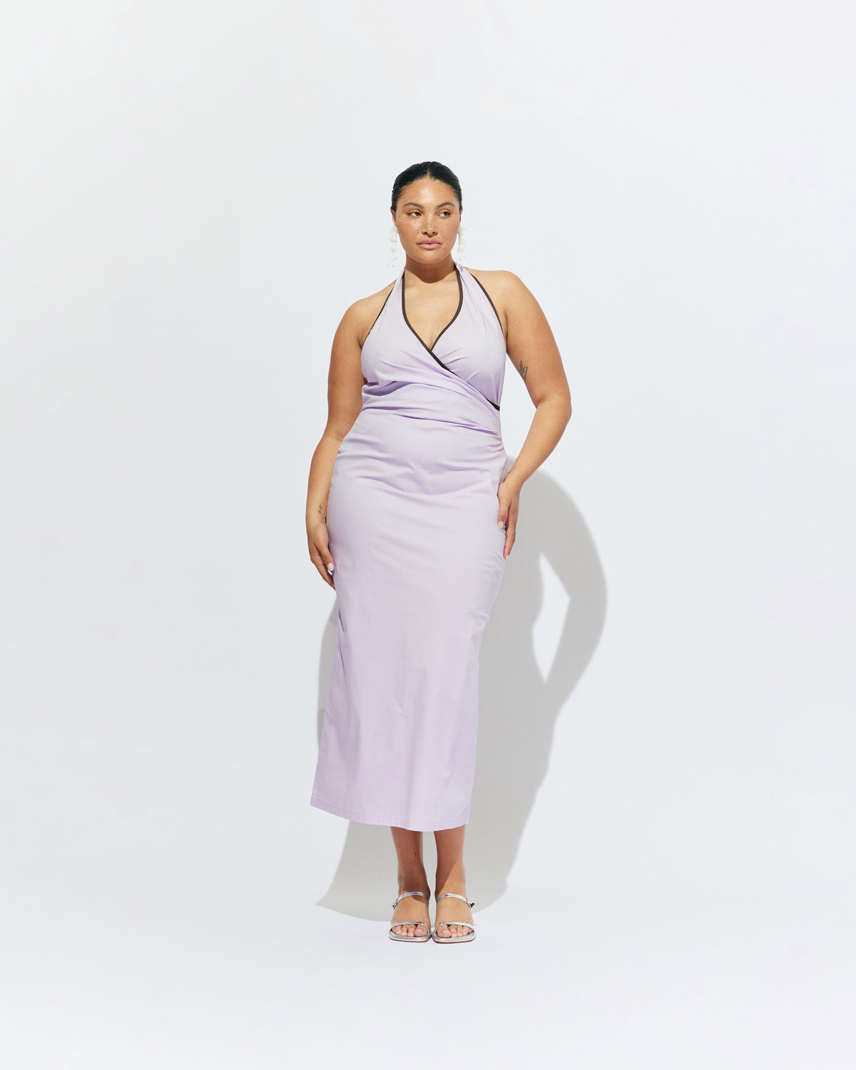 JOEY DRESS LILAC | Bias cut midi dress with a tie-up halter neckline, crafted in our lilac organic cotton. Designed with ruching details on the waist and back for a tailored fit through the body, which falls into a straight cut skirt with a...
