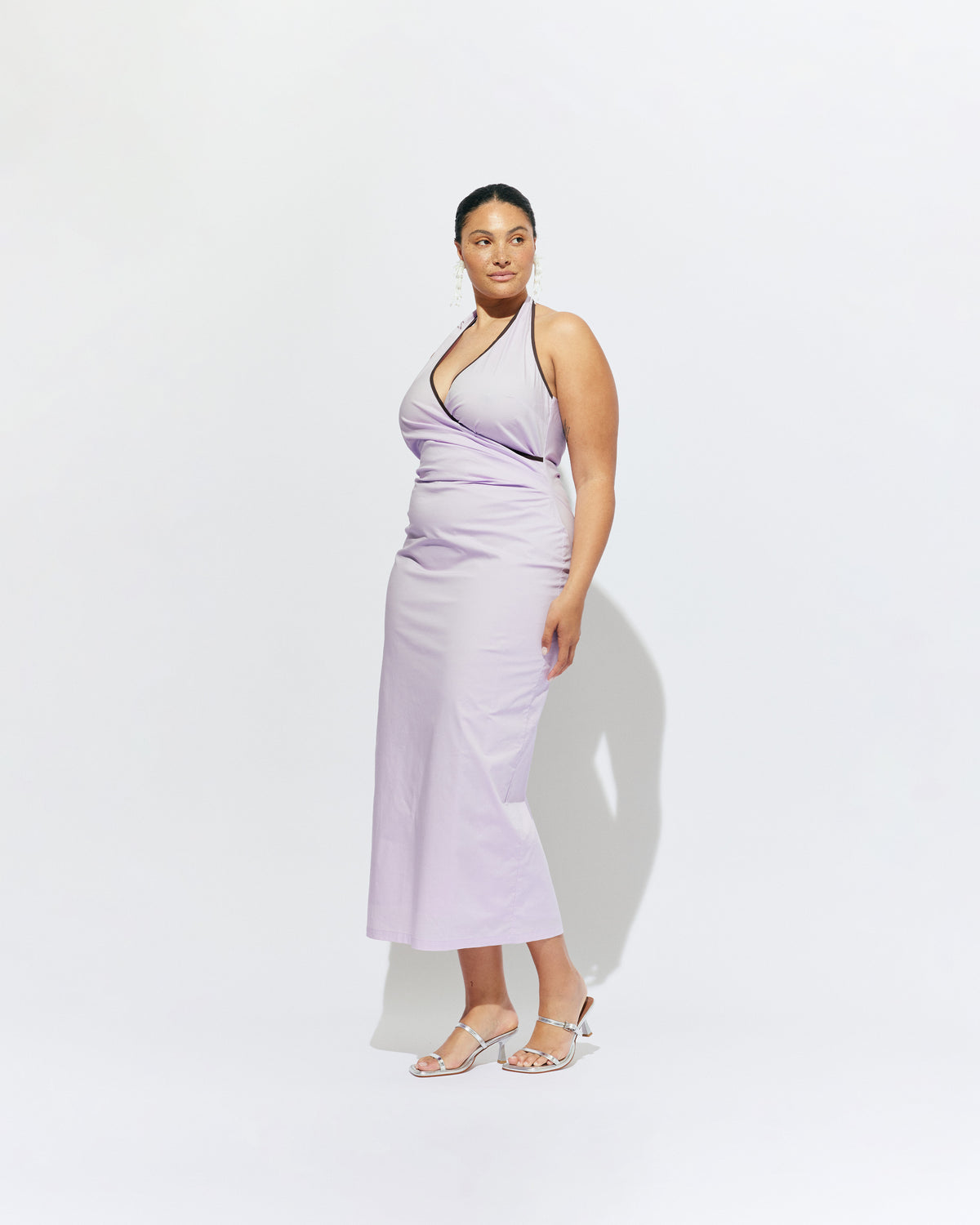 JOEY DRESS LILAC | Bias cut midi dress with a tie-up halter neckline, crafted in our lilac organic cotton. Designed with ruching details on the waist and back for a tailored fit through the body, which falls into a straight cut skirt with a...