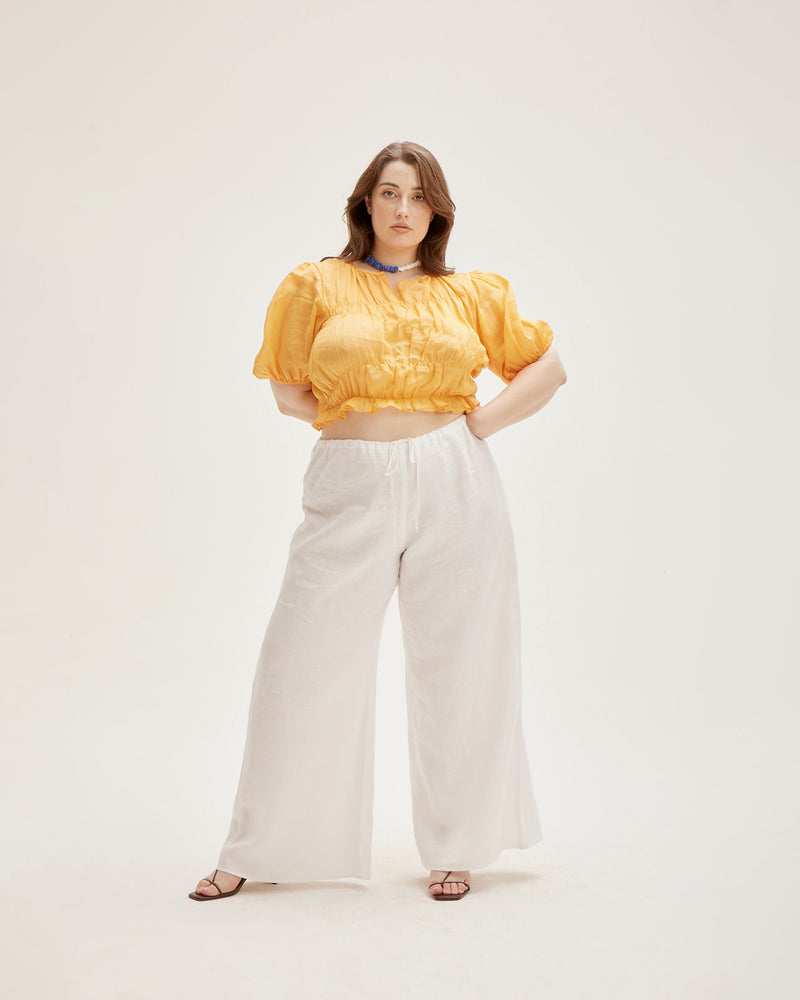 LILLIE TOP MARIGOLD | Elasticated crop blouse with with puff sleeves and a frill hem, made from a delicate translucent ramie voile. The elastic detail creates texture in the piece, and contrasts with the...