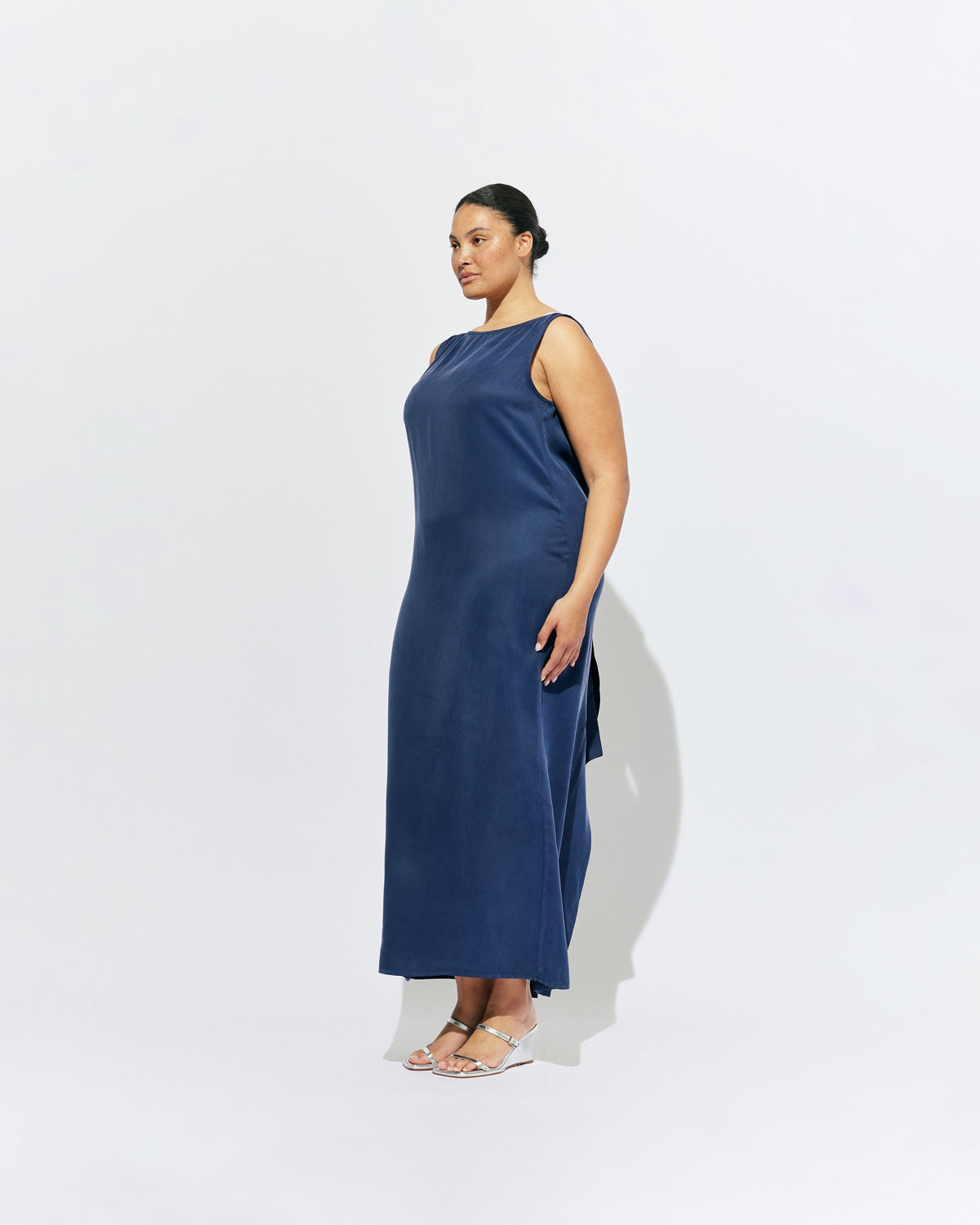 LIZ GOWN MULHOLLAND NAVY CUPRO | Liz is a relaxed fit sleeveless gown with a wrap feature, accentuated with long waist ties, that can be tied around the body or at the back in a bow. Imagined in a buttery soft navy magnolia cupro. 