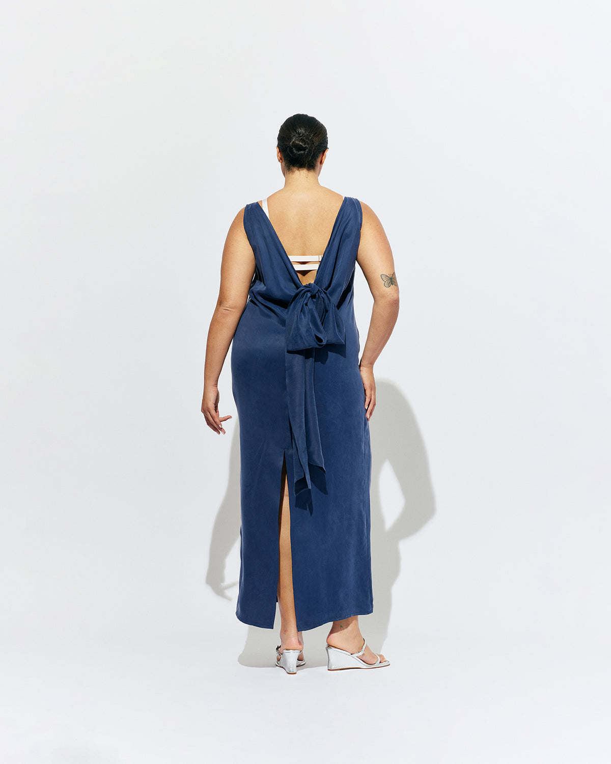 LIZ GOWN MULHOLLAND NAVY CUPRO | Liz is a relaxed fit sleeveless gown with a wrap feature, accentuated with long waist ties, that can be tied around the body or at the back in a bow. Imagined in a buttery soft navy magnolia cupro. 