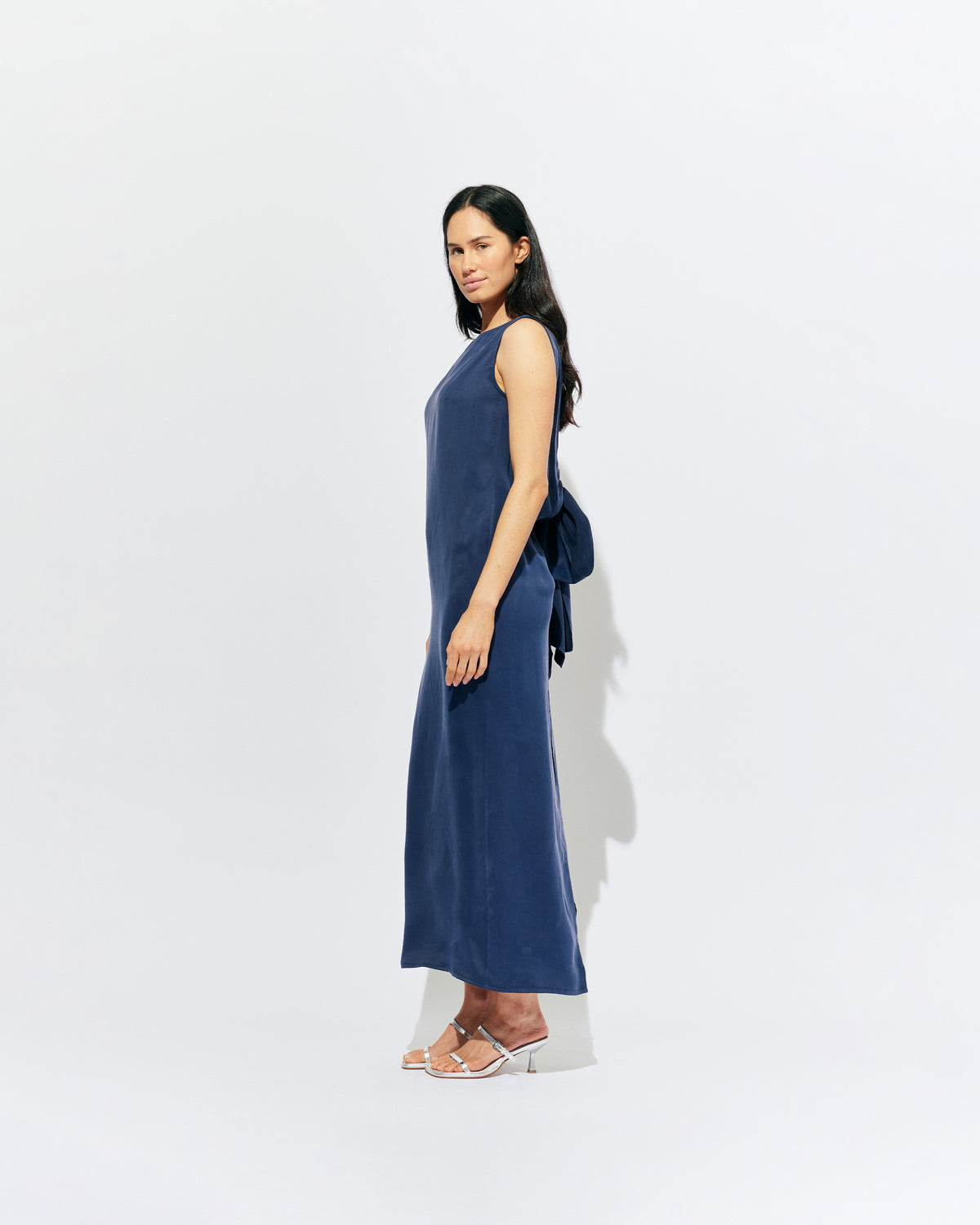 LIZ GOWN MULHOLLAND NAVY CUPRO | Liz is a relaxed fit sleeveless gown with a wrap feature, accentuated with long waist ties, that can be tied around the body or at the back in a bow. Imagined in a buttery soft navy magnolia cupro. 