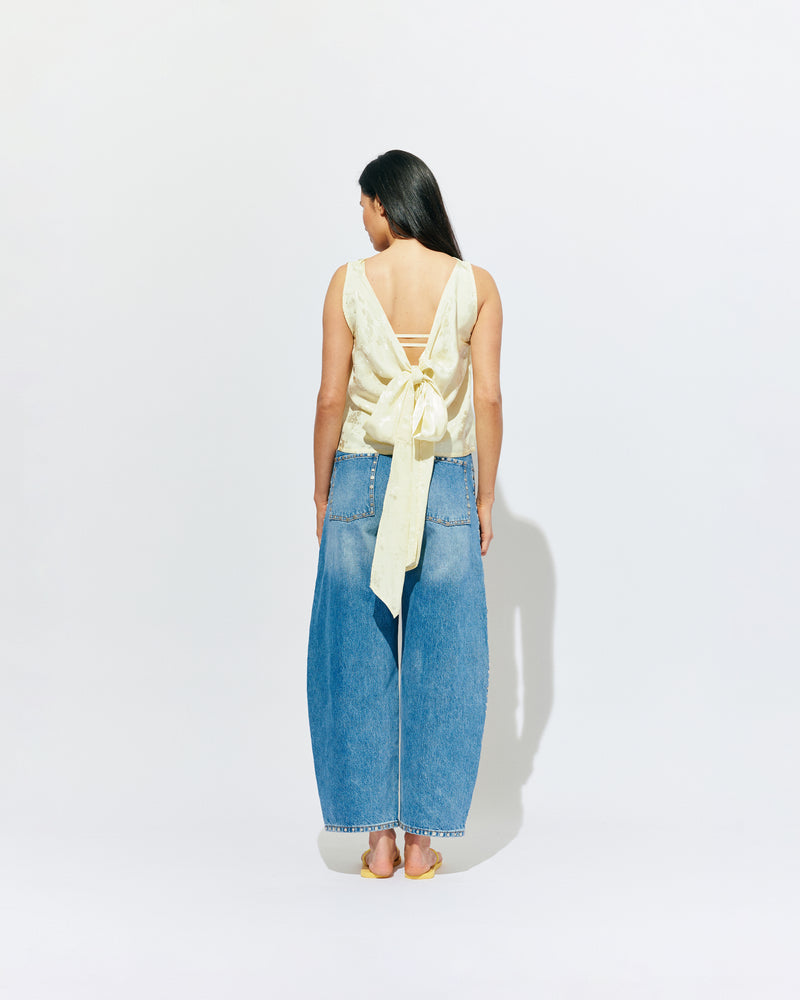 LIZ TOP BUTTER JACQUARD | Liz is a relaxed fit sleeveless top with a wrap feature, accentuated with long waist ties that can be tied around the body or at the back in a bow. Imagined in a sheeny jacquard satin, when this fabric catches...