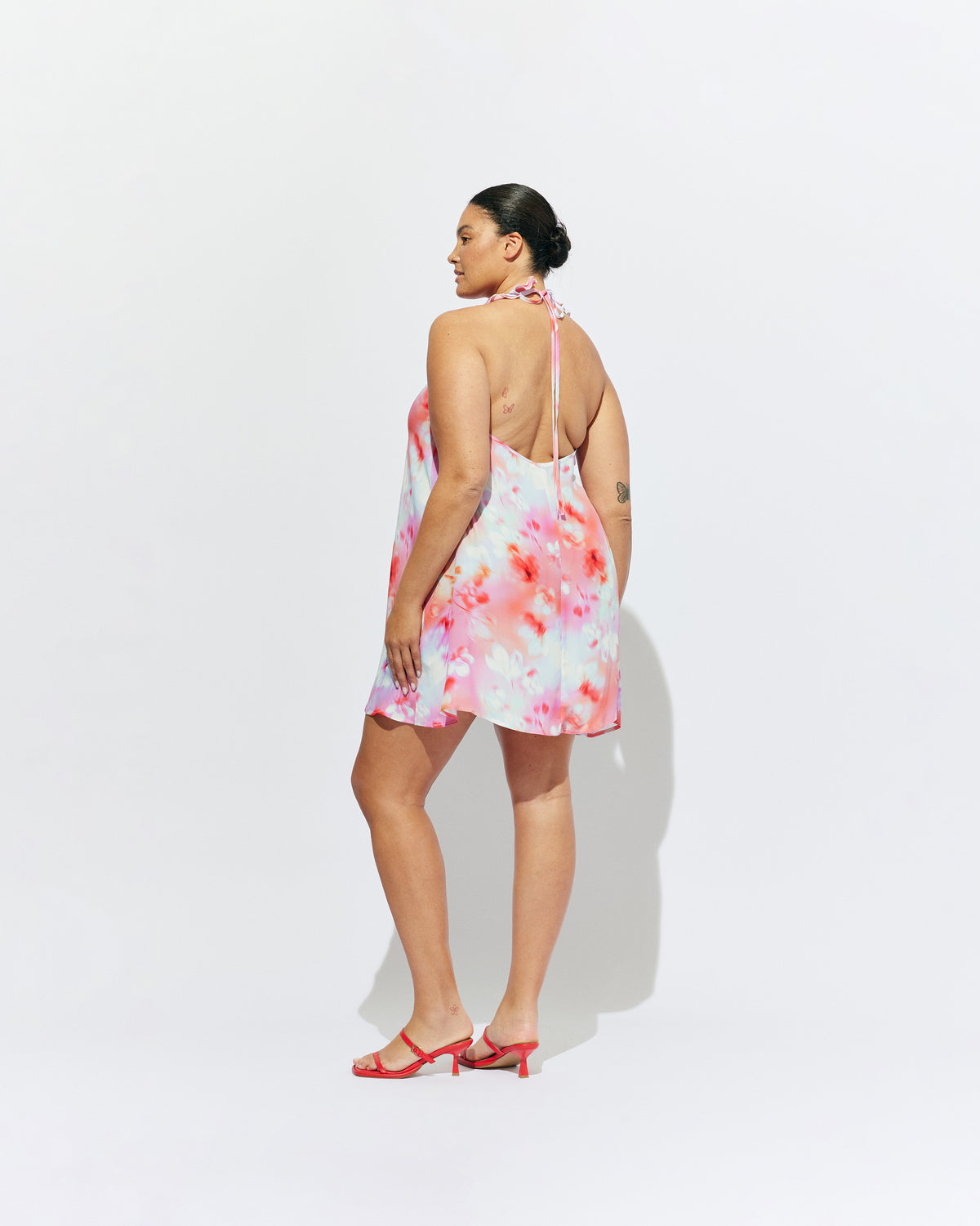 PASSIONFRUIT HALTER MINI DRESS GLOWY FLORAL | Floaty mini dress with feature ruffles along the neckline and an open back, designed in our glowy floral print. Features considered details with two side pockets and an adjustable tie at the neck, which make this an easy pick in...
