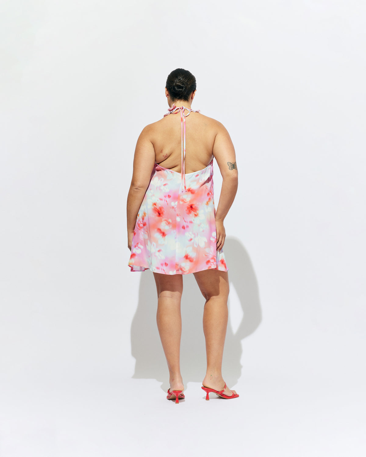PASSIONFRUIT HALTER MINI DRESS GLOWY FLORAL | Floaty mini dress with feature ruffles along the neckline and an open back, designed in our glowy floral print. Features considered details with two side pockets and an adjustable tie at the neck, which make this an easy pick in...