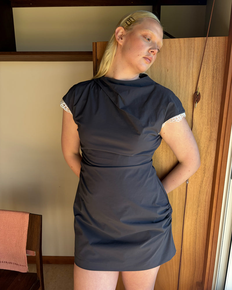 BOWIE MINI DRESS CHARCOAL | Mini dress crafted in a charcoal organic cotton, featuring a high neck collar, lace trim, and gathered detailing on the lower back and side seam, designed for better fit and movement. Perfect for any occasion, this versatile piece is a...