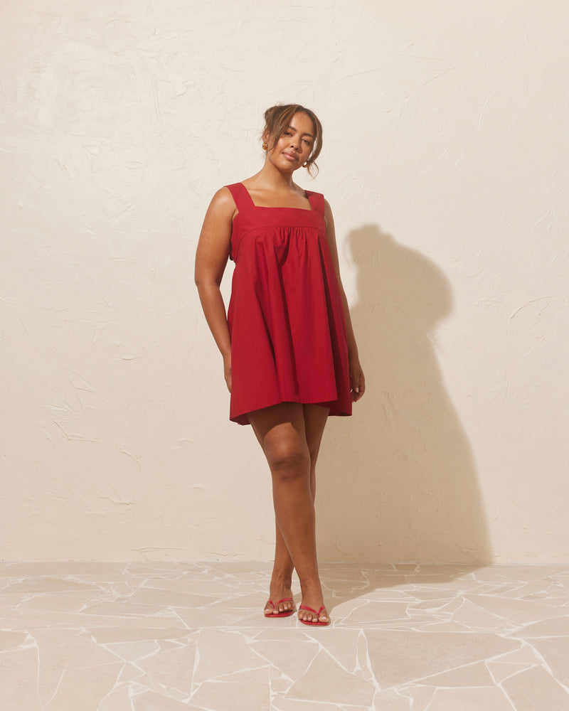 MARGIE TIE MINI DRESS GARNET | Cotton mini dress with a square band bust. The skirt falls into an A-line shape with an exposed back and bow tie closure.