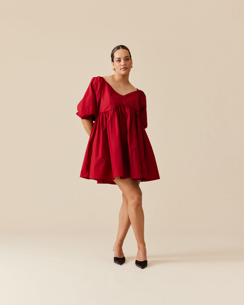 NONI MINI DRESS GARNET | Baby doll mini dress crafted in a garnet red cotton. Features panelling at the bust that falls to a soft, A-line gathered skirt and puff sleeves.
