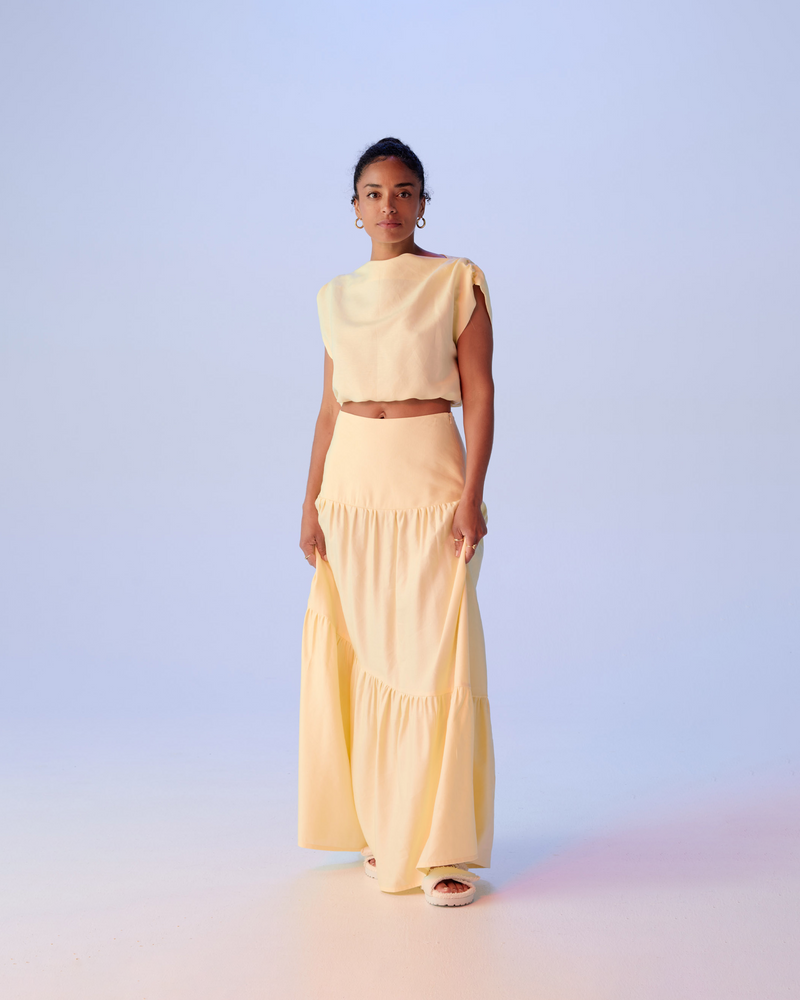 BONITA LINEN CROP BUTTER | Cropped top with a mini cap sleeves and an open tie closure at the back neck, crafted in a soft butter coloured linen. This top has an elasticated hem, meaning...