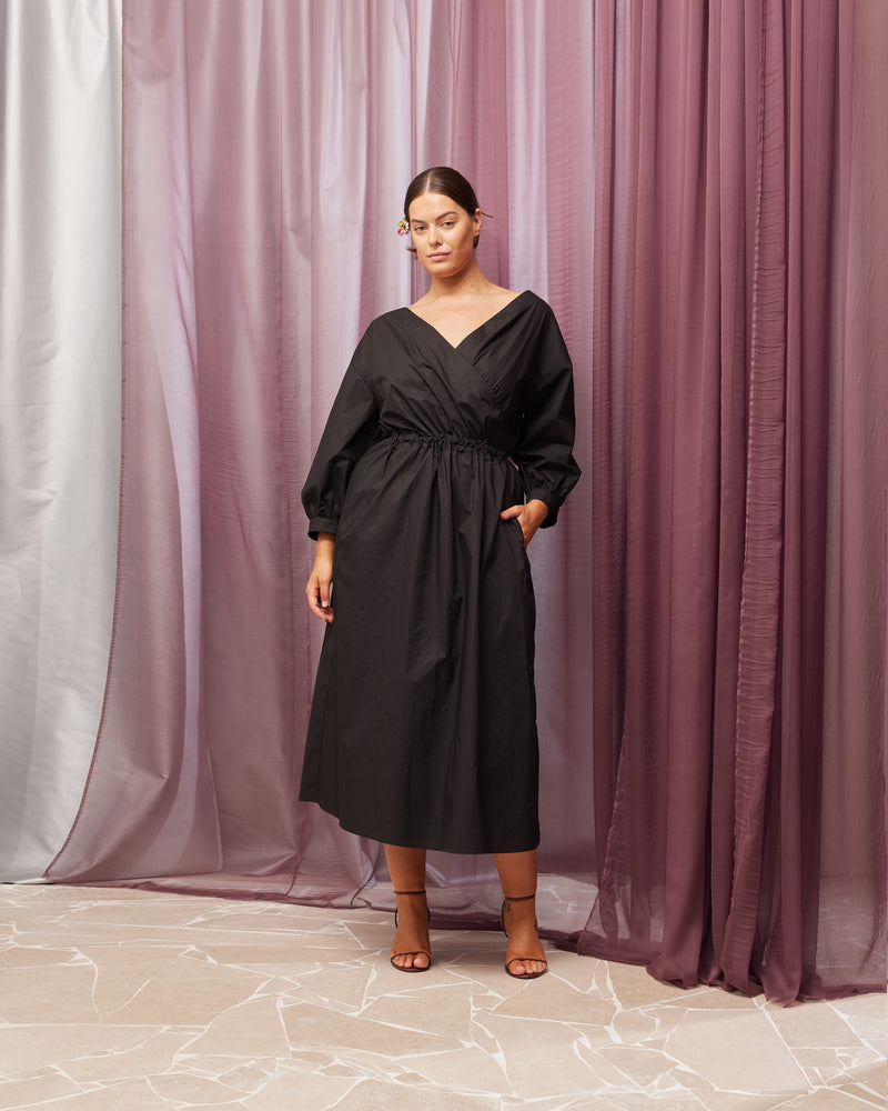 DELILAH WRAP DRESS BLACK | Cotton midi dress with an elasticated waist and has cuffs at the sleeves. This dress has a faux wrap detail and pockets to house all your essentials.