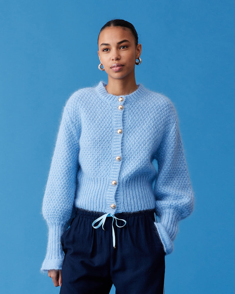 MATILDA CARDIGAN SKY BLUE | Button-down cardigan with gold metallic dome buttons and a slightly puff-shouldered silhouette. Features an exaggerated flute cuff crafted in a chunky mohair and wool blend.